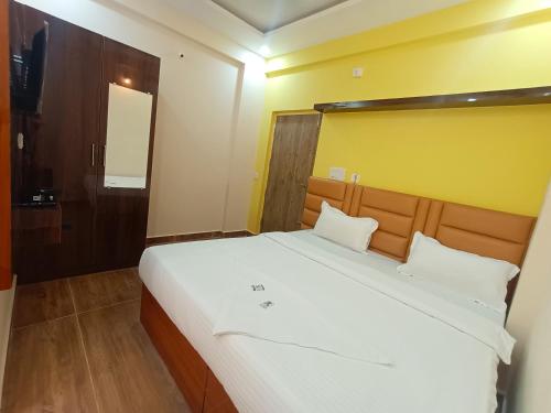 a bedroom with a large white bed with a yellow wall at STAYMAKER Karanji Paradise - Next to Liquor station in Bangalore