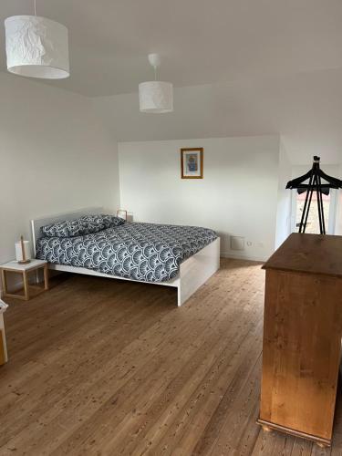 een slaapkamer met een bed en een houten vloer bij Le gîte de la rue in Gréville-Hague