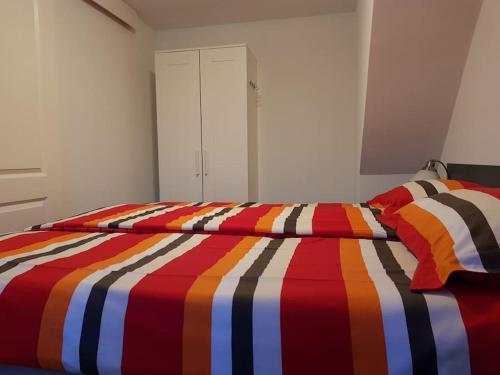 2 Betten mit bunter gestreifter Bettwäsche in einem Schlafzimmer in der Unterkunft Modern zomerhuis voor 4 personen in Wijk aan Zee