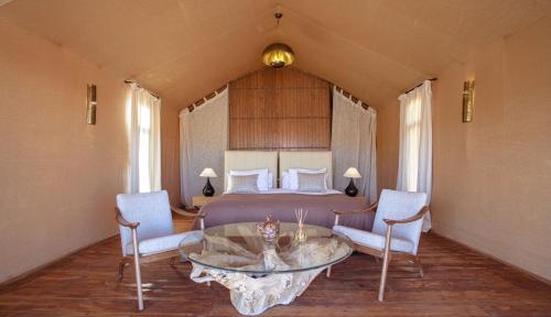 a bedroom with a bed and a table and chairs at Erg Chebbi Luxury Desert Camp in Merzouga