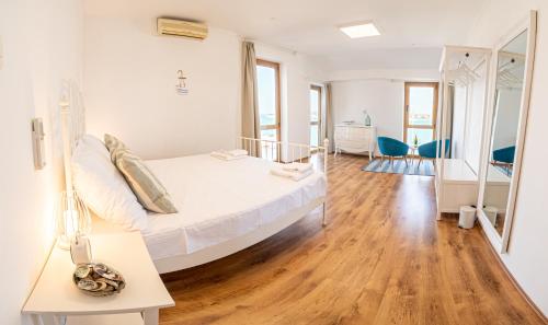 a white bedroom with a bed and a wooden floor at Umag seafront seaview center apartments old town 1,2,3,4 by Rentistra in Umag