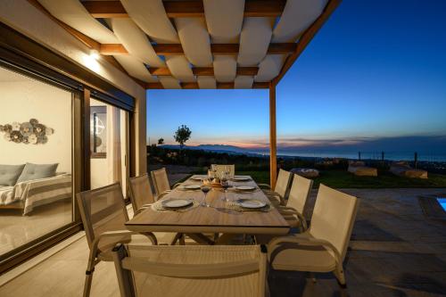 een eetkamer met een tafel en stoelen op een patio bij Jason Panorama Villa 2 in Skouloúfia