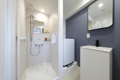 a white bathroom with a shower and a sink at IKEBUKURO MANGA HOUSE in Tokyo