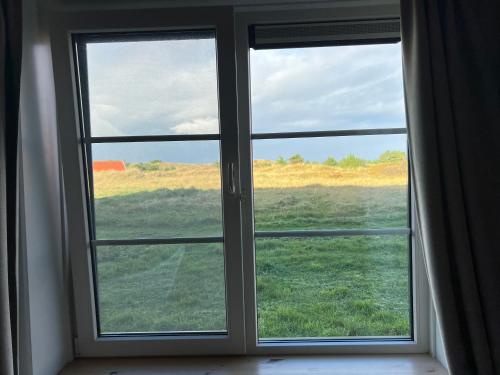 une fenêtre avec vue sur un champ verdoyant dans l'établissement Hotel Posthuys Vlieland, à Oost-Vlieland