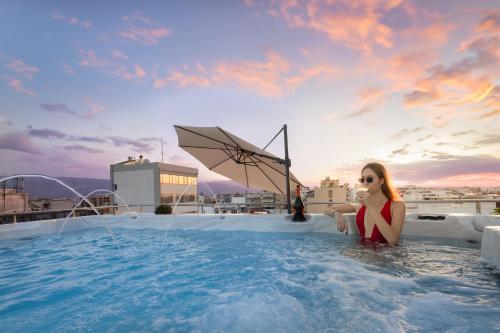 a woman sitting in a hot tub on a roof at Epavli Grace Hotel in Chania Town