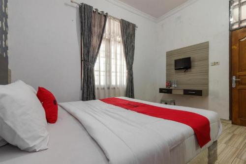 a bedroom with a white bed with red pillows and a window at RedDoorz @ Pantai Panjang Bengkulu in Pekansaptu