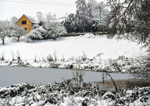 un cortile coperto da neve con una casa e un laghetto di Badgers Sett a Chipping Campden