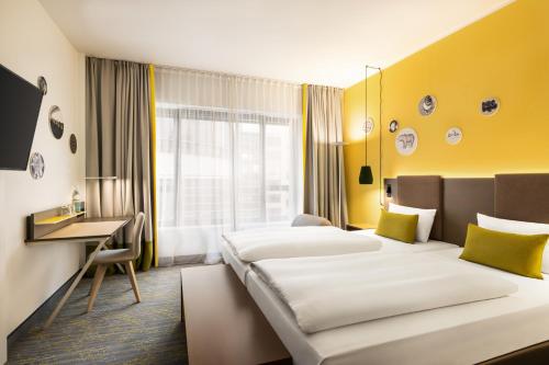 ein Hotelzimmer mit zwei Betten und einem Schreibtisch in der Unterkunft Vienna House Easy by Wyndham Berlin Prenzlauer Berg in Berlin