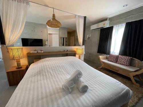 a bedroom with a large white bed and a mirror at Grand Rock Studio Samui in Lamai