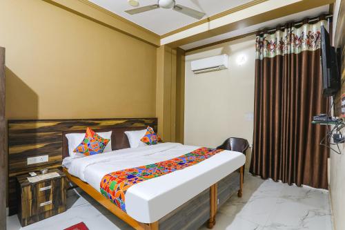 um quarto com uma cama e uma televisão em FabHotel SR em Varanasi