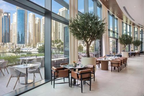 a restaurant with tables and chairs and large windows at Vida Dubai Marina & Yacht Club Residences in Dubai