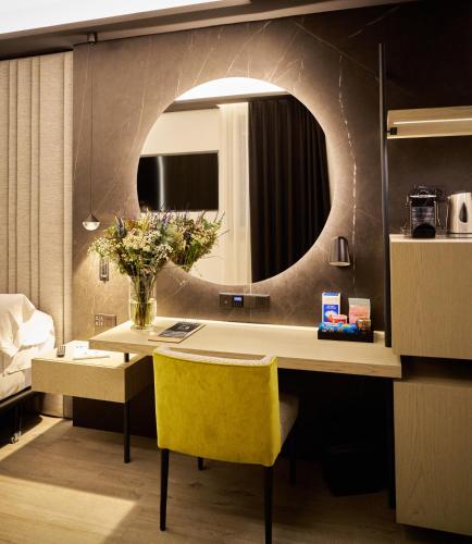 a room with a desk with a yellow chair and a mirror at Hotel Regina in Madrid