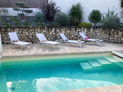 2 chaises longues et une piscine avec un mur de retenue dans l'établissement Villa climatisée avec piscine à St Remy, à Saint-Rémy-de-Provence