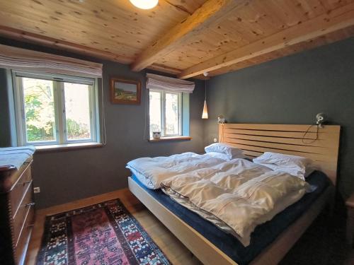 a bedroom with a bed with a wooden headboard and two windows at Holsteinshof in Jübek