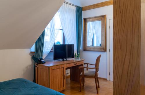 een slaapkamer met een bureau, een tv en een stoel bij Dwór Prezydencki Boutique Hotel & SPA in Tarnów