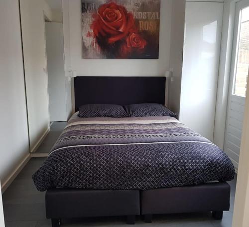 a bed in a bedroom with a red rose on the wall at Zomerhuisje 18K - 1 km van het strand in Wijk aan Zee