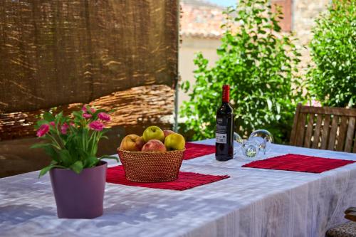 a table with a bottle of wine and a basket of fruit at Alojamiento Rural Fuente del Arca (Prádena del Rincón) in Prádena del Rincón