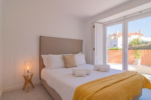 a white bedroom with a large bed and a large window at Chalet Maria da Assunção in Estoril