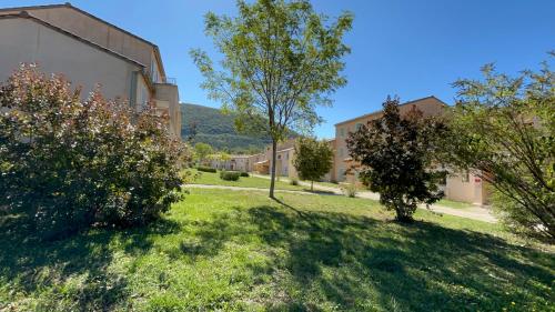 a green yard with trees and a building at Olydea Montbrun-les-Bains in Montbrun-les-Bains