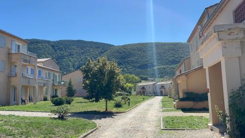 a street in a town with houses and a mountain at Olydea Montbrun-les-Bains in Montbrun-les-Bains