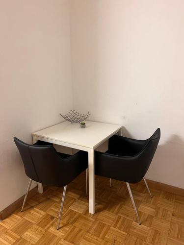 einen weißen Tisch und zwei schwarze Stühle in einem Zimmer in der Unterkunft EasyRoomBasel in Basel
