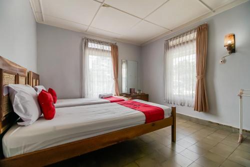 una camera da letto con un grande letto con cuscini rossi di RedDoorz near Jam Gadang Syariah Bukit Tinggi a Bukittinggi
