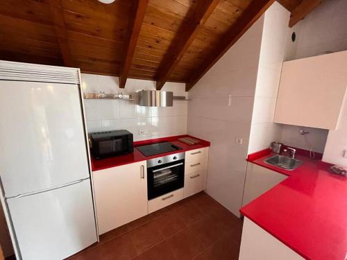małą kuchnię z białymi urządzeniami i czerwonymi blatami w obiekcie Villa Quijano w mieście Casasola