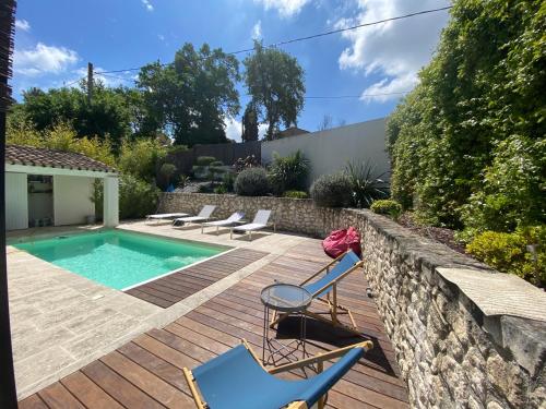 une arrière-cour avec une piscine et des chaises sur une terrasse en bois dans l'établissement Villa climatisée avec piscine à St Remy, à Saint-Rémy-de-Provence