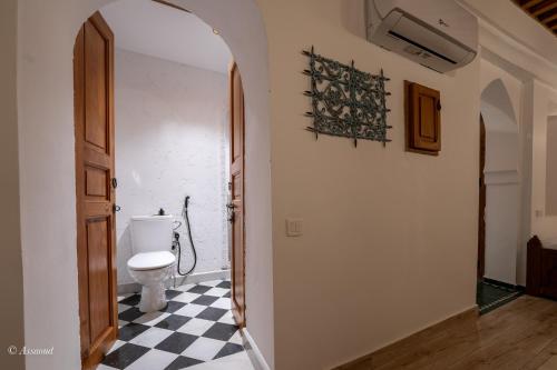 a bathroom with a toilet and a black and white checkered floor at Riad Dar Chama in Chefchaouene