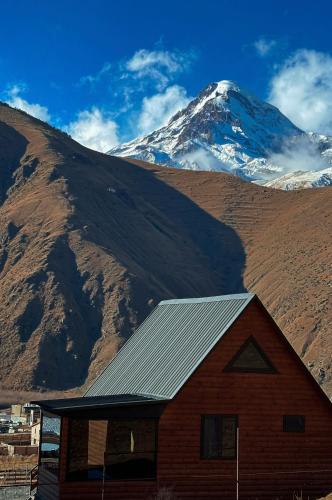 a barn with a snow covered mountain in the background at Kazbegi Inn Cottages in Stepantsminda