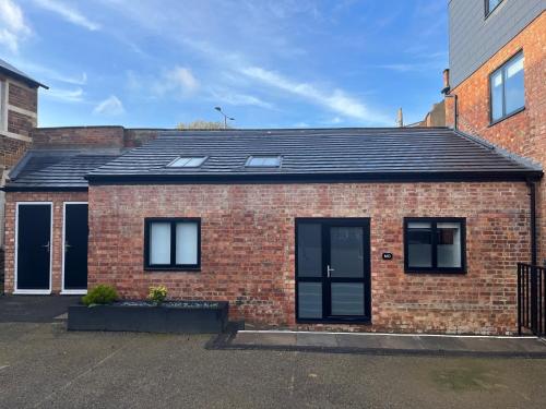 a red brick house with a black roof at Barn Conversion, Town Centre, Brand new, Beautiful designed, light, fresh and spacious, Secure parking option, Netflix TV ready, Wifi in Wellingborough
