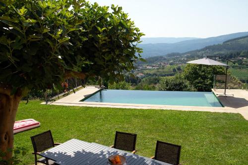 a pool with a table and chairs in the grass at Villa 282 in Calheiros