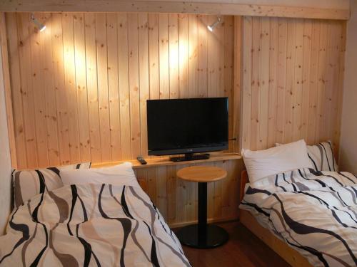 a room with two beds and a television on a table at Pension Locomotion in Kutchan