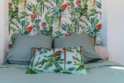 1 cama con 2 almohadas y papel pintado con motivos florales en La Terrasse suspendue des Arènes - Une Nuit à Nîmes, en Nimes