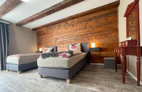 een slaapkamer met 2 bedden en een houten muur bij Ferienwohnung mit WiFi und 2 Schlafzimmern - b45533 in Ipsheim
