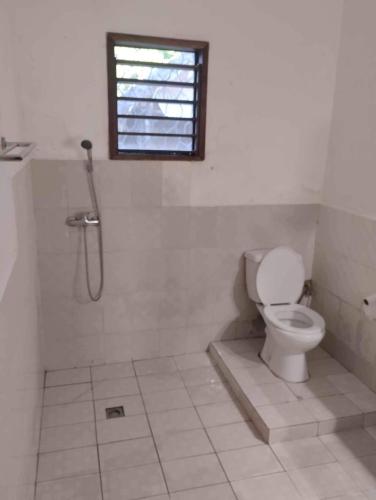 a bathroom with a toilet and a shower with a window at Villa charme bord de mer in Ambondrona