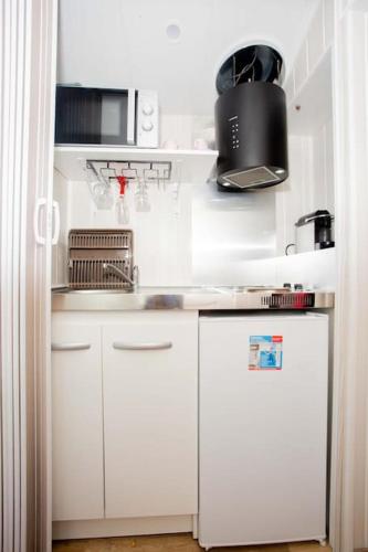 une petite cuisine avec des armoires blanches et un évier dans l'établissement Love House SPA SAUNA terrasse, à Aulnay-sous-Bois