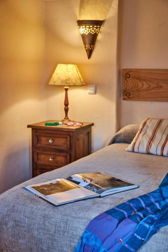 a book on a bed with a lamp on a night stand at Casa Rural Fuente del Arca Montejo in Montejo de la Sierra