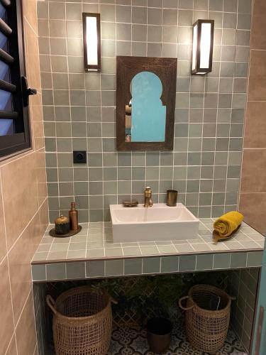 baño con lavabo, espejo y cestas en Le Riad Private Pool, en Saint-Pierre