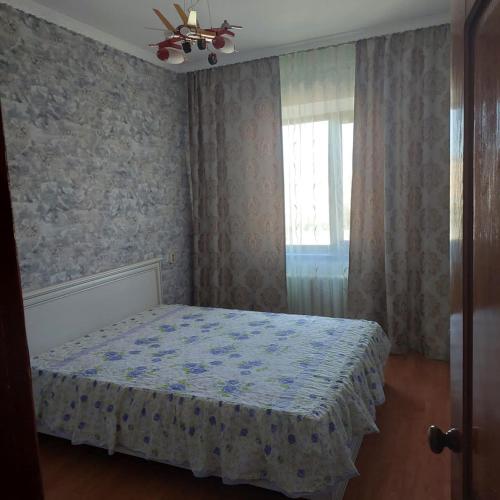 1 dormitorio con cama y ventana en 3-х комнатная по ул. Есенова 19А, en Kyzylorda
