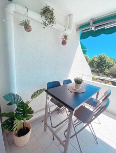 une table et des chaises dans une pièce avec des plantes dans l'établissement Appartement typeT2bis climatisé à 150m de la plage, à La Grande Motte