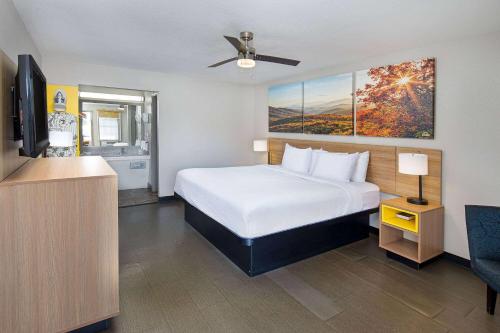 a hotel room with a bed and a flat screen tv at Days Inn by Wyndham Holladay in Holladay