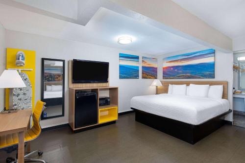a hotel room with a bed and a flat screen tv at Days Inn by Wyndham Holladay in Holladay