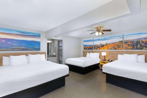 a hotel room with two beds and a ceiling fan at Days Inn by Wyndham Holladay in Holladay