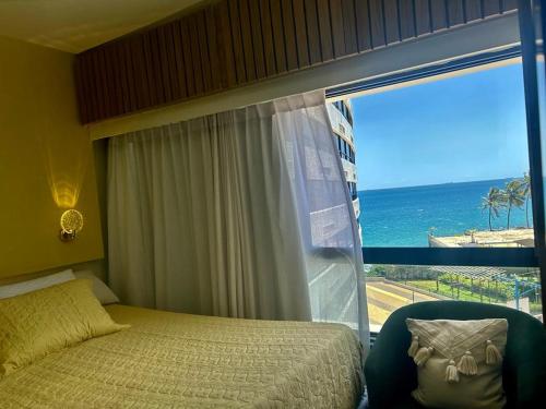 a bedroom with a bed and a view of the ocean at apart hotel 2 quartos frente mar in Salvador