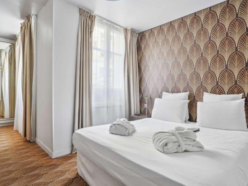 1 dormitorio con 1 cama blanca grande y toallas. en Mercure Paris Opéra Faubourg Montmartre, en París