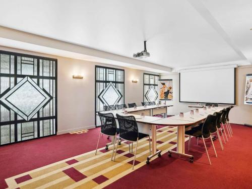 une salle de conférence avec une grande table et des chaises ainsi qu'un tableau blanc dans l'établissement Mercure Paris Opéra Faubourg Montmartre, à Paris