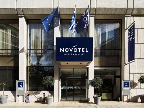 a building with flags in front of a novouc headquarters at Novotel Athens in Athens