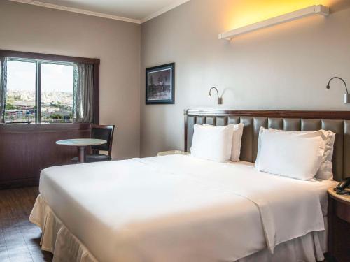 um quarto de hotel com uma cama grande e uma janela em Mercure Uberlândia Plaza Shopping em Uberlândia