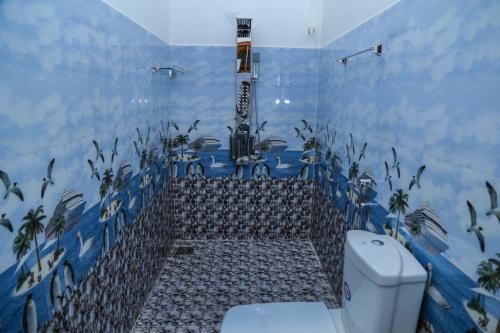 a bathroom with a toilet and a blue tiled wall at Cinnamon City in Hikkaduwa